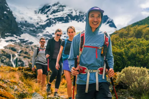 Two men and women hiking on a trail with foggy mountains in the background
