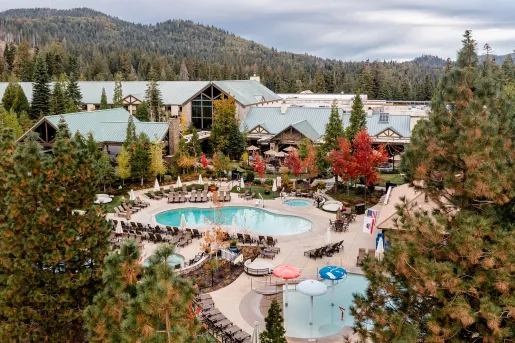 Exterior sky view of large wooden buildings with blue roofs, and outdoor pools in front