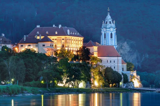 Exterior view of large hotel complex with a clocktower on the right, in front of a large lake