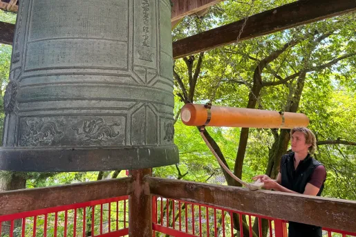 Man looking at a large bell in a temple
