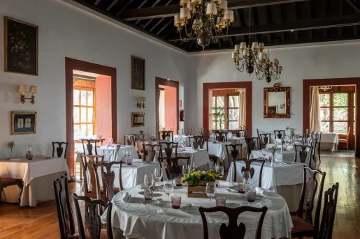 Restaurant with circular tables with white table clothes, and wooden chairs
