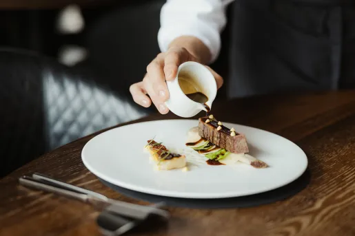 Man pouring chocolate over a plate with dessert