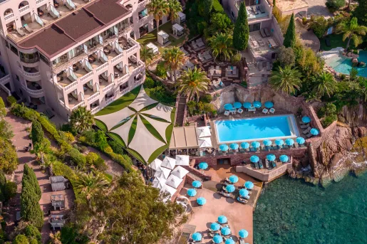 Sky view of a hotel building with an outdoor pool and blue umbrellas