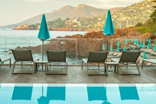 Outdoor pool with reclining chairs facing the ocean