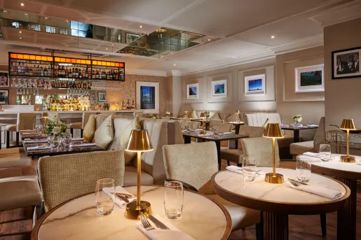 Restaurant with circular tables and beige, cushioned chairs