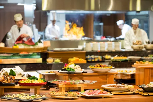 Buffet style tables with plates of food and 4 chefs in the background