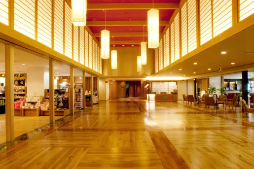 Hotel lobby area with wooden flooring and long lamps hanging from the ceiling
