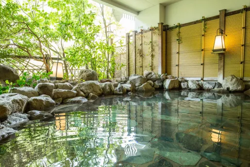 Outdoor hot tub bath surrounded by large rocks and bamboo plants