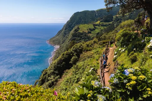 Group of people hiking on a dirt trail, with the ocean to the left
