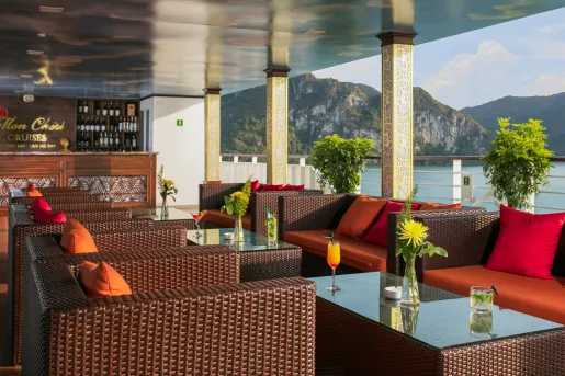 Outdoor patio  with woven, cushioned chairs with views of the ocean in the background
