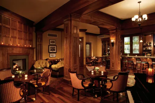 Dimly lit restaurant with wooden walls, and cushioned chairs surrounding dining tables