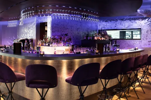 Bar and lounge with tall stools and purple lights along the walls