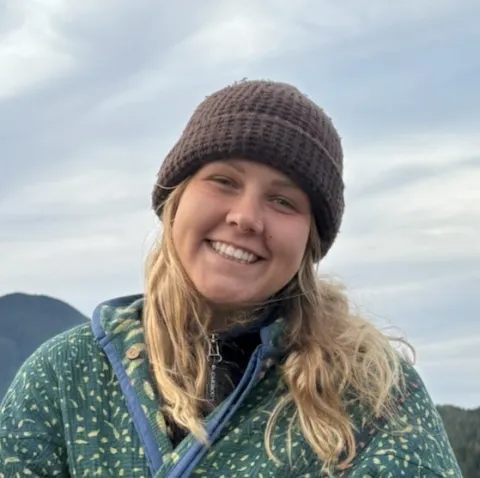 Woman with blonde hair and a brown beanie, smiling