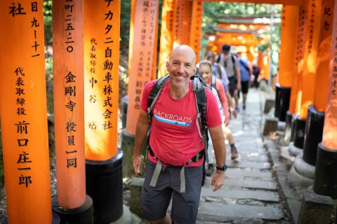 Walking up a hill among orange arches in Japan