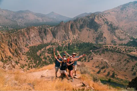 Guests with their arms raised, enjoying a hike in Oregon’s rugged high desert wonderland