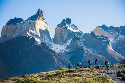 Large mountains with a group of people walking on a smaller mountain