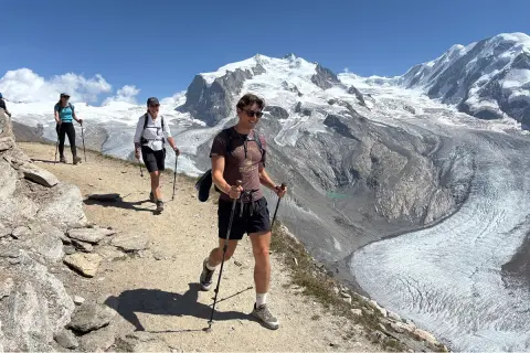 Group of people descending a gravel trail with mountains in the background