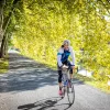 Guest/leader cycling down tree-covered road, smiling.