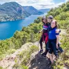 Three young guests posing together, overlooking large lake, hillside.