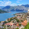Aerial view of buildings all along the shore of a body of water, mountains in the distance