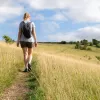 Woman walking through a field of tall weeds in a valley