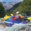 Group of people on a blue raft, paddling through an active river