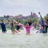Group of kids in the ocean with their hands in the air