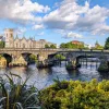 Stone bridge over a river leading to a castle-like building