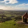Woman on top of a hill with a stone pillar looking out to a large valley