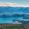 Sky view of a large lake, surrounded by tall mountains and trees