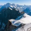 Top view of snowcapped mountains with larger mountains in the distance