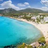 Beach with blue water and a small, coastal town to the right