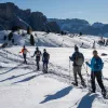 Group of hikers walking through a snowy valley with tall mountains in the distance