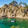 Large cliffs by the ocean shore, with a boat floating in the water