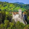 Castle on top of a cliff, surrounded by tall hills and grassy fields