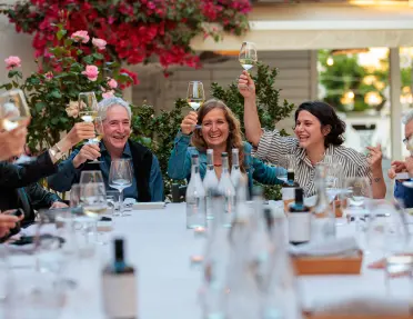Group of guests at meal, toasting wine glasses.