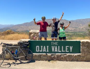 Guests behind "OJAI VLLEY" sign.