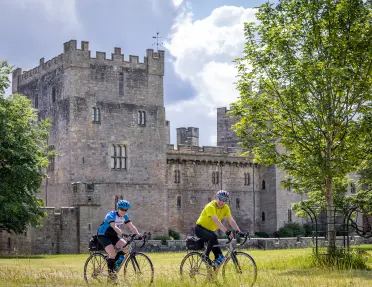 cyclists ride by a castle