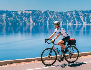 Woman smiling while riding a bike next to a large lake