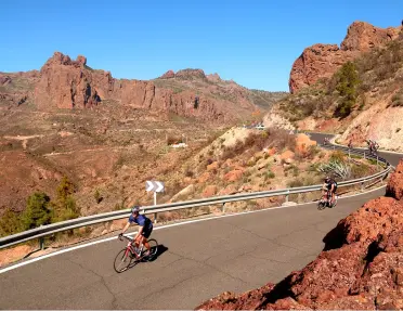 Person biking on a road with large canyons in the background