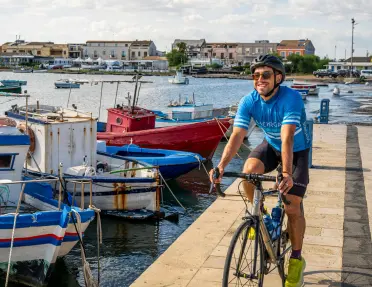 Backroads guest rides a bike along the boat marina.