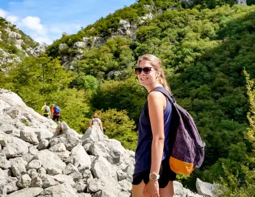 Woman looking back and smiling, hiking on a large mountain