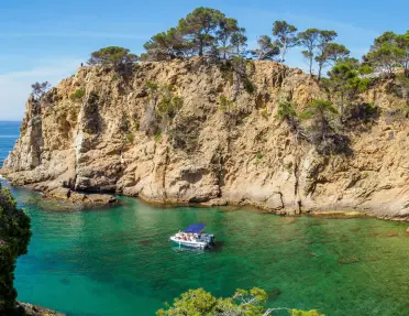 Large cliffs by the ocean shore, with a boat floating in the water