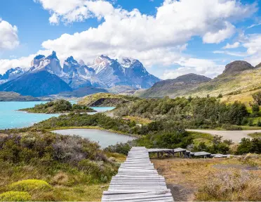 Long, wooden bridge leading to a lake in a valley