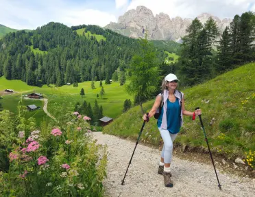 A Backroads guest on a hike in the Dolomites, surrounded by lush green trees and pink flowers.